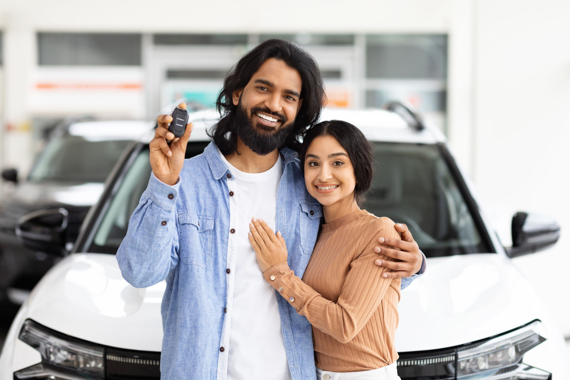 Two people embracing and holding their new car keys